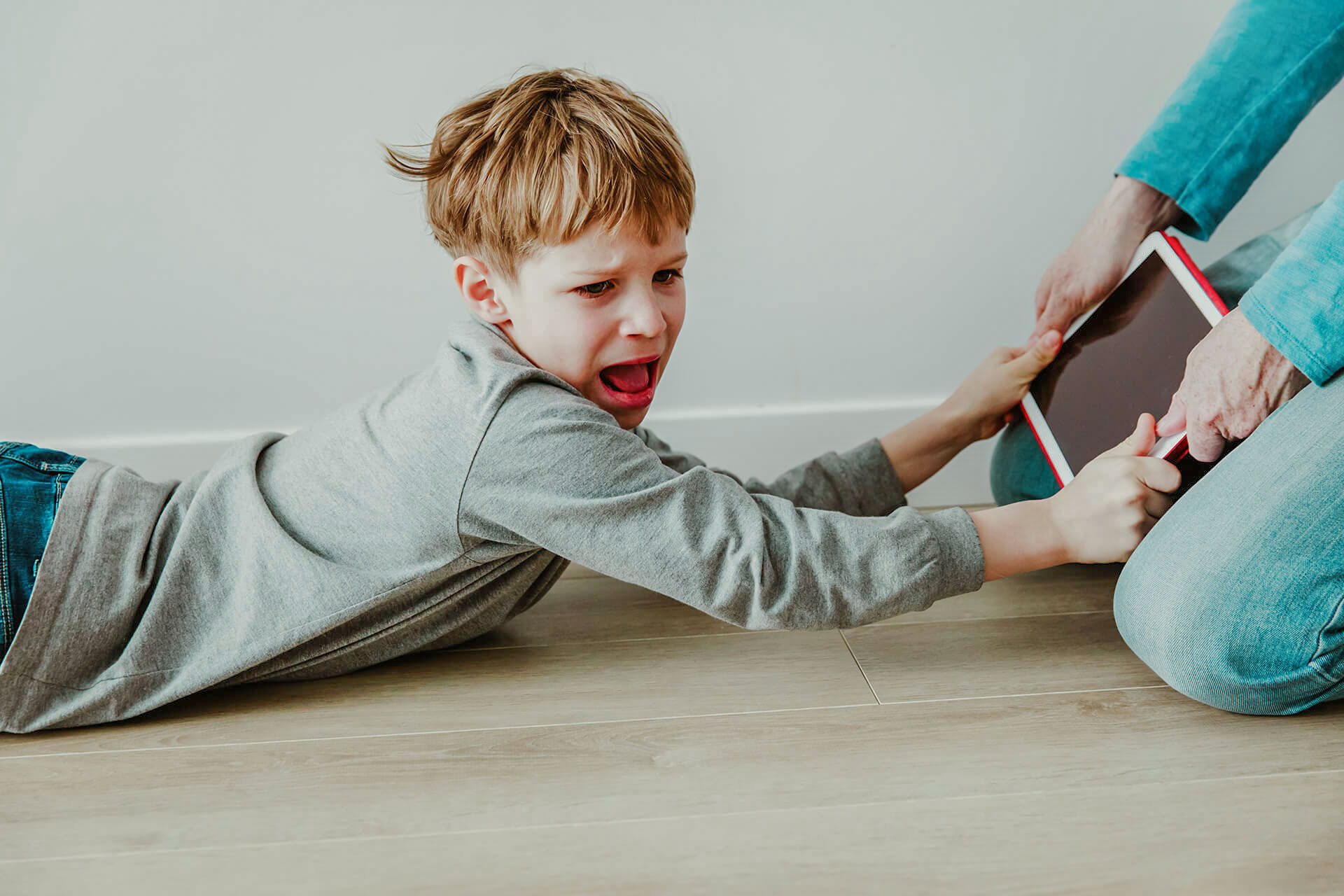 Enfant en pleurs refusant de lâcher un iPad pendant une crise du bacon